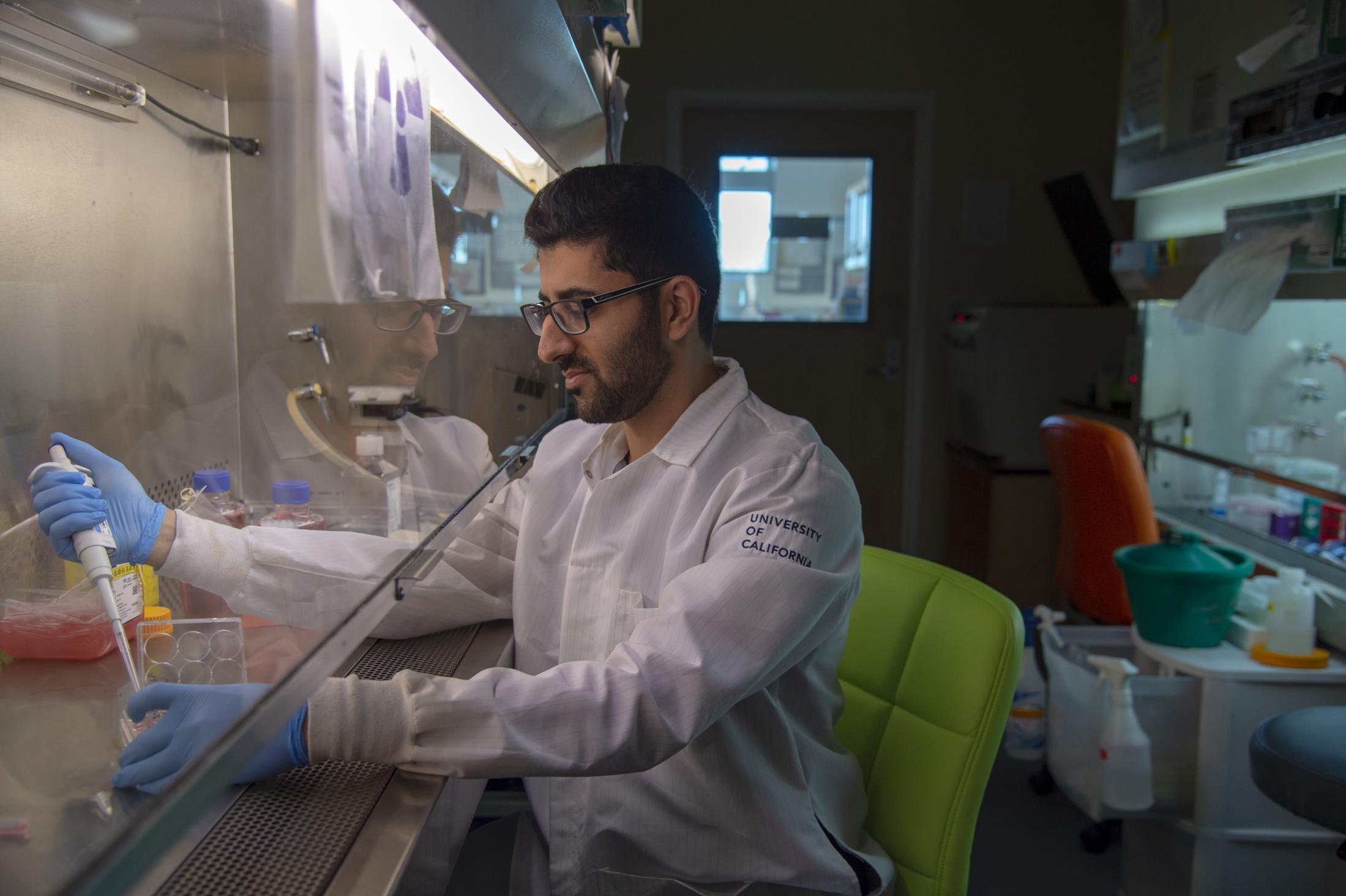 UC Entrepreneurship Academy Amir Bolandparvaz in the lab wearing ppe using a pipette in a fumehood
