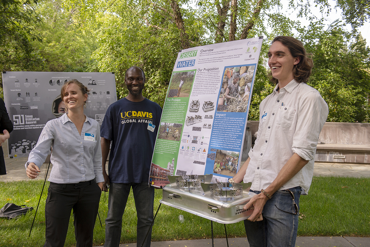 three student entrepreneurs with their business competition poster