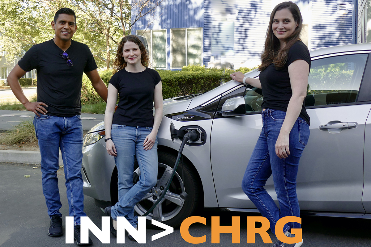 image of one male and two females standing next to electric vehicle charging outdoors