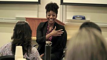 woman in business attire speaking in front of a classroom 
