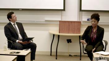 man and woman, both in business attire, seated and talking