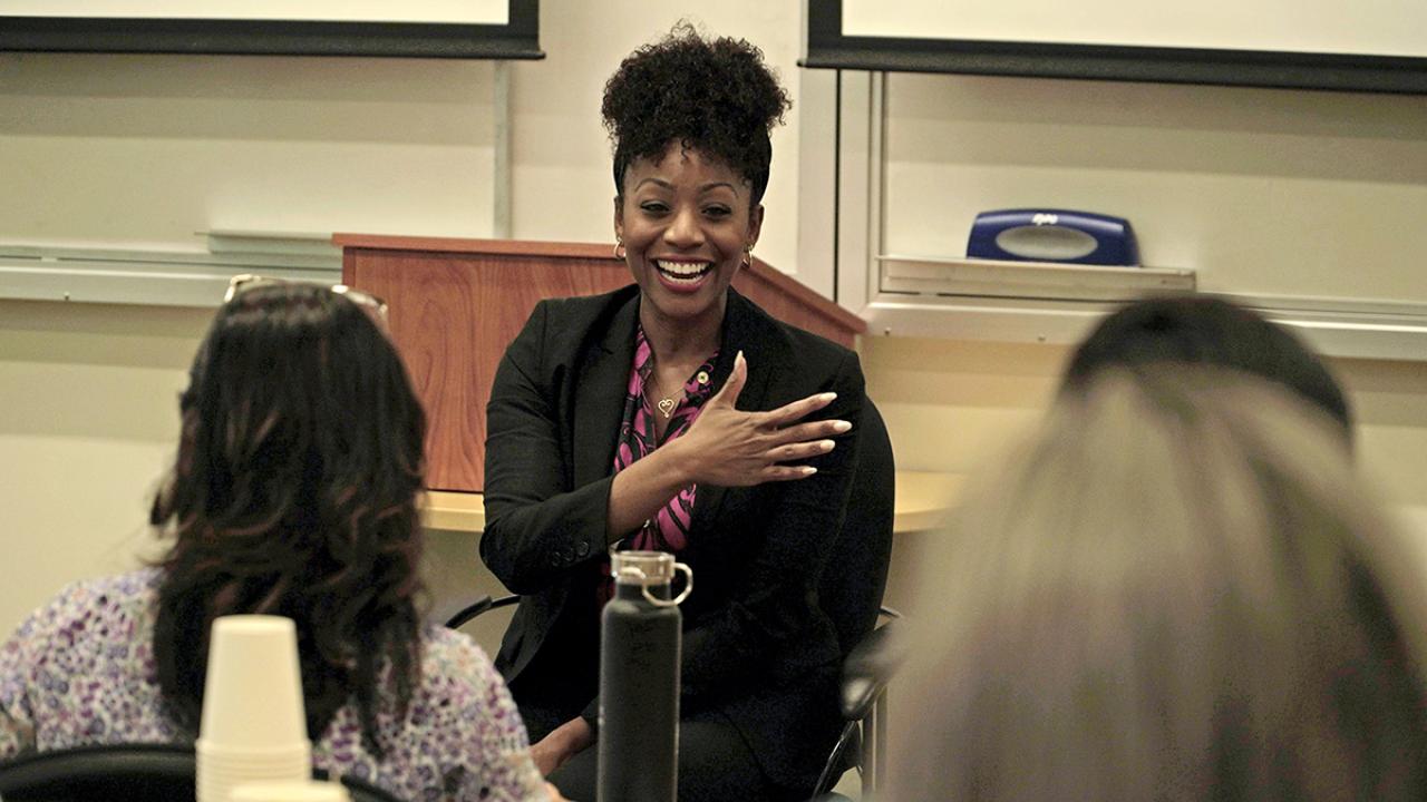 woman in business attire speaking in front of a classroom