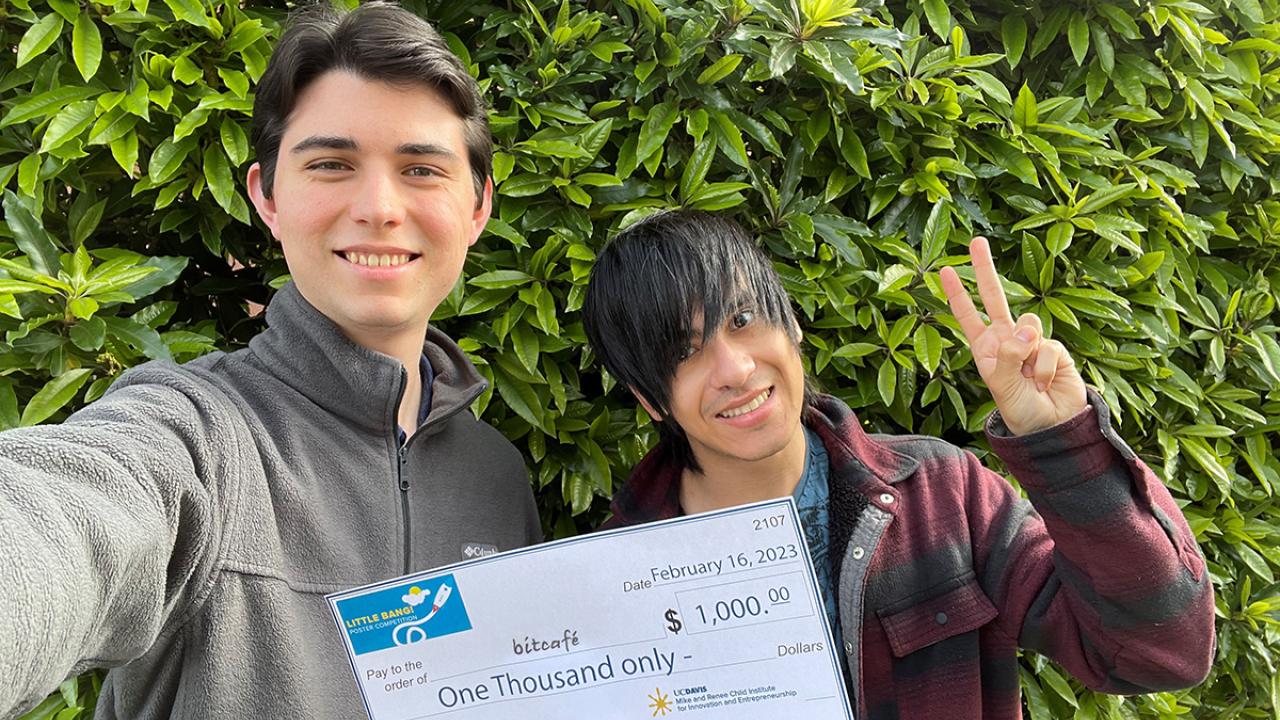 photo of two undergraduates holding a large check