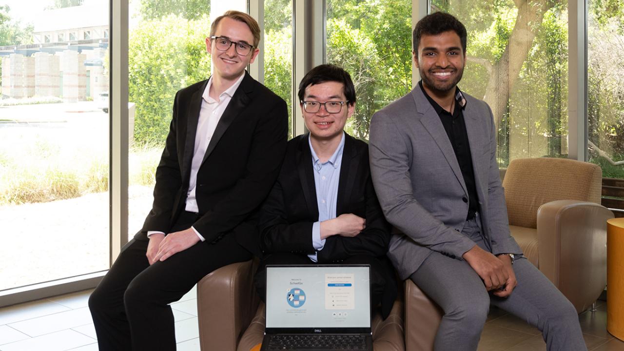 three young men showing their startup's website on a laptop