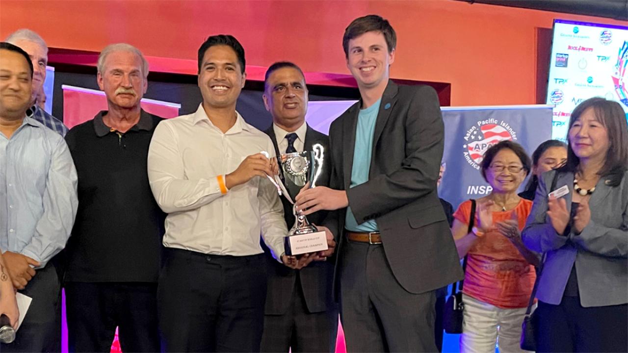 young entrepreneur receiving trophy for winning contest while many look on
