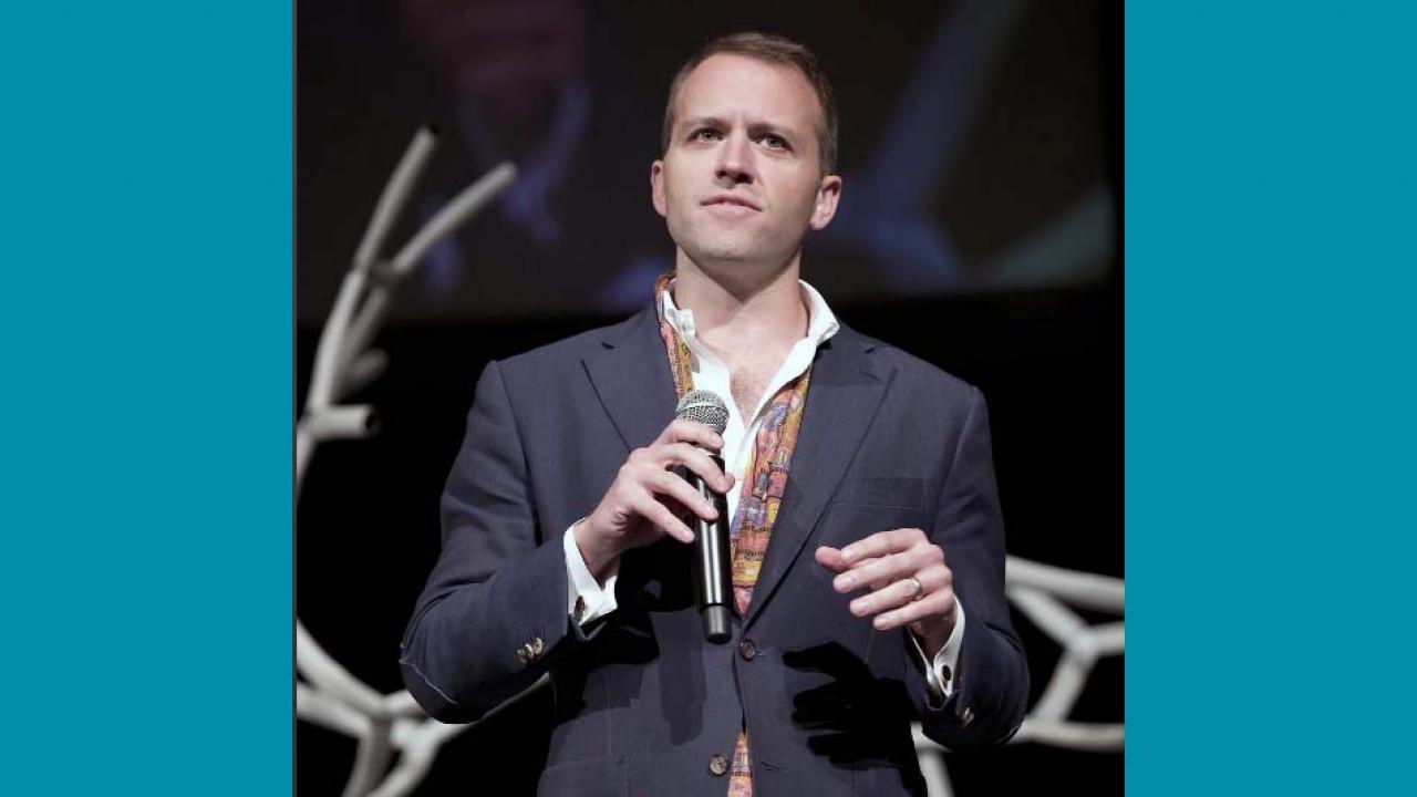 man presenting on stage with microphone