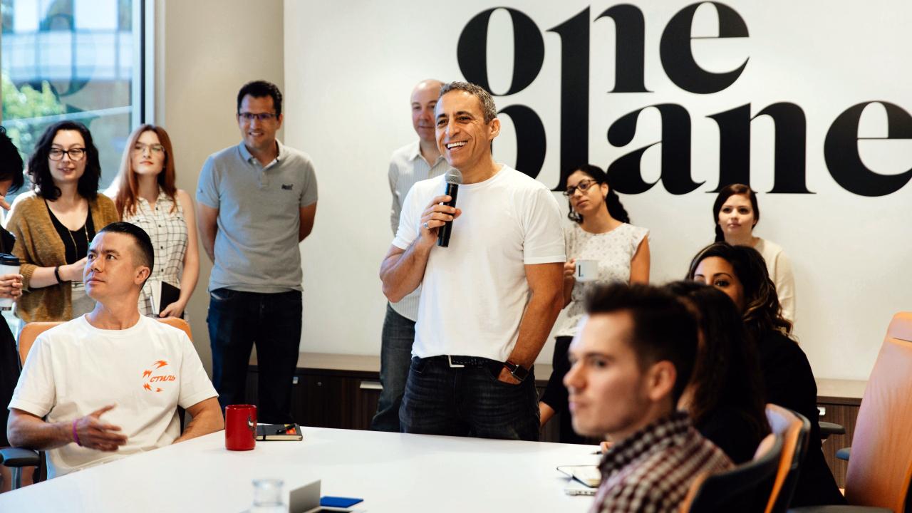 image of group of people in a room with one man speaking with a microphone and text on wall "one planet"