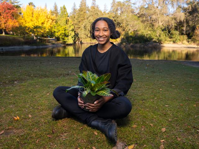 photo of a graduate student sitting outdoors with a plant