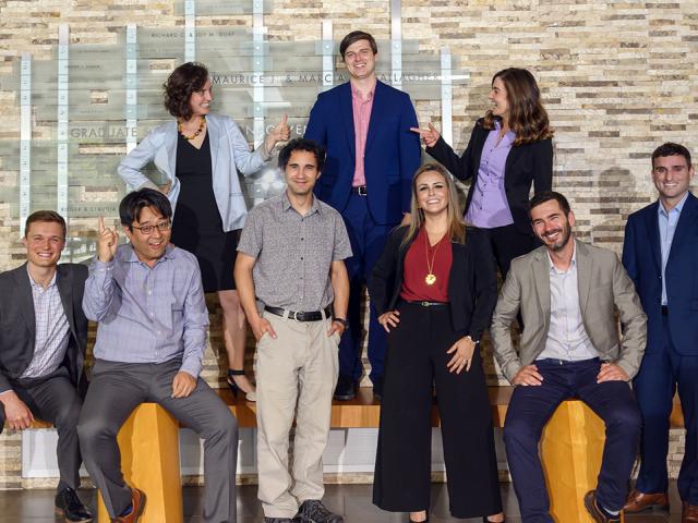 image of nine people standing and sitting indoors