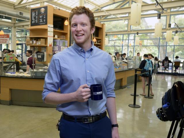 male fellow standing in coffee house with coffee mug