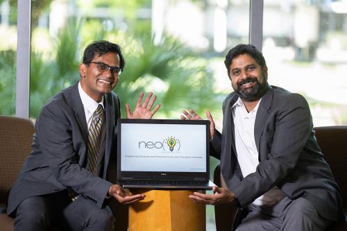 photo of two men sitting and showing their startup website on a laptop
