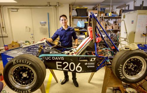 mechanical engineering undergraduate student in his lab with race car model