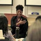 woman in business attire speaking in front of a classroom 