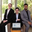 three young men showing their startup's website on a laptop