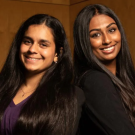 Simran Lallian and Jaya Athuluru pose back to back against a brown background.
