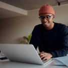 young man with orange hat sitting at desk with notebook