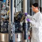 scientist in lab coat and ppe working on equipment at Origin Materials’ West Sacramento facility.