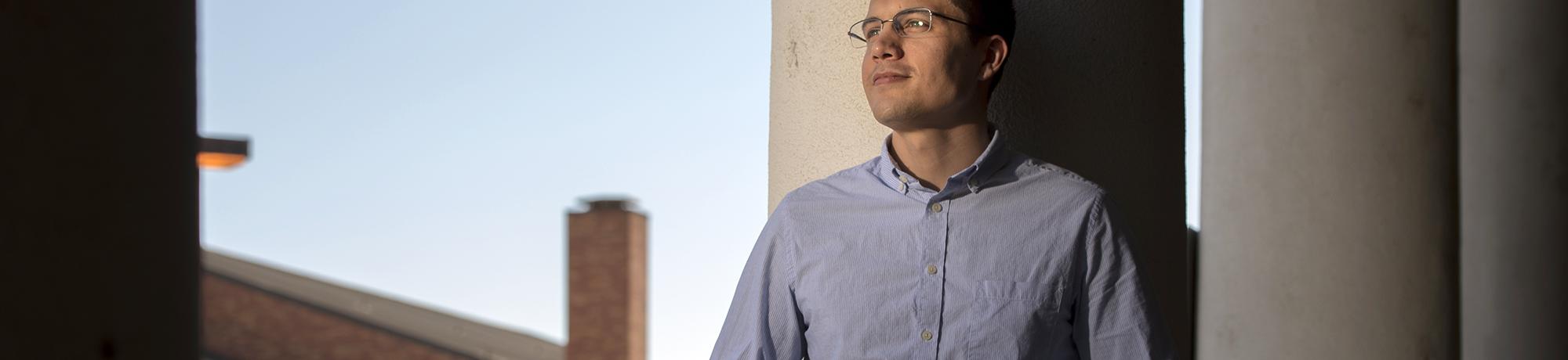 male grad student standing by academic building