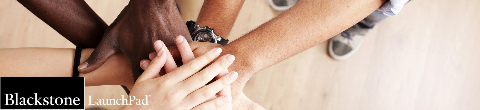 photo of pile up of hands with a logo in the bottom left corner